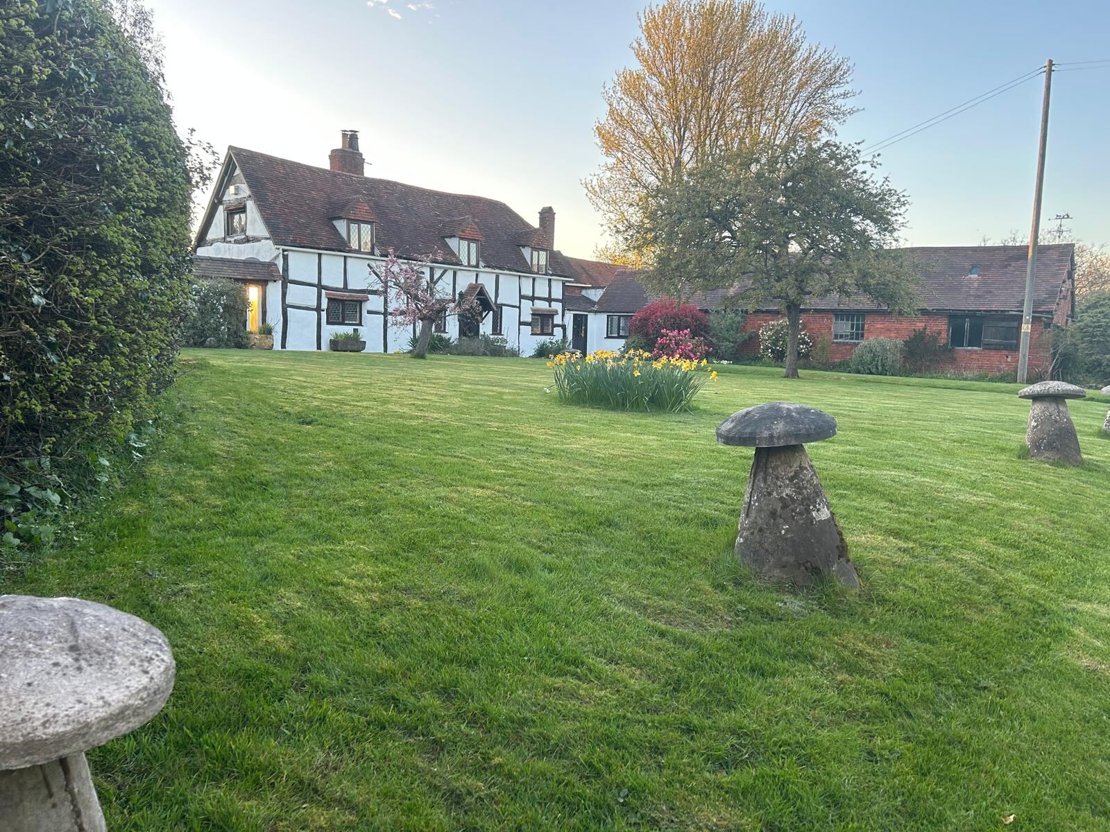 The cottage and barn with staddle stones on the lawn